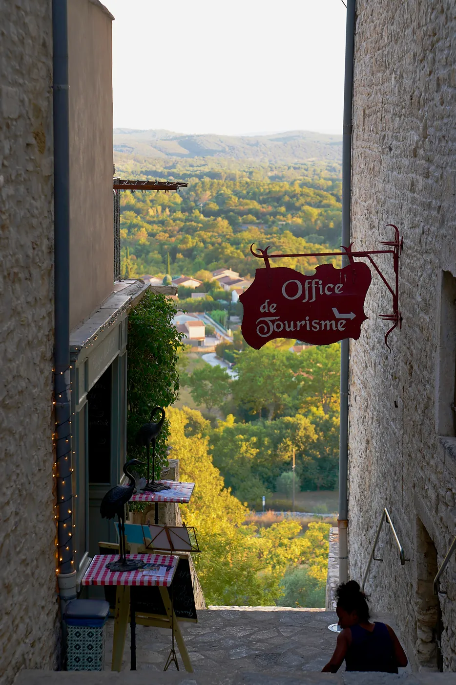A young woman reading a book on stairs going down toward the valley.