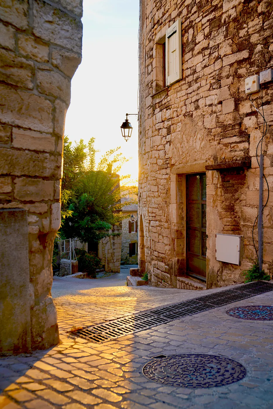 The sunset peeking around the corner of a side street branching off of l'Grand Rue.