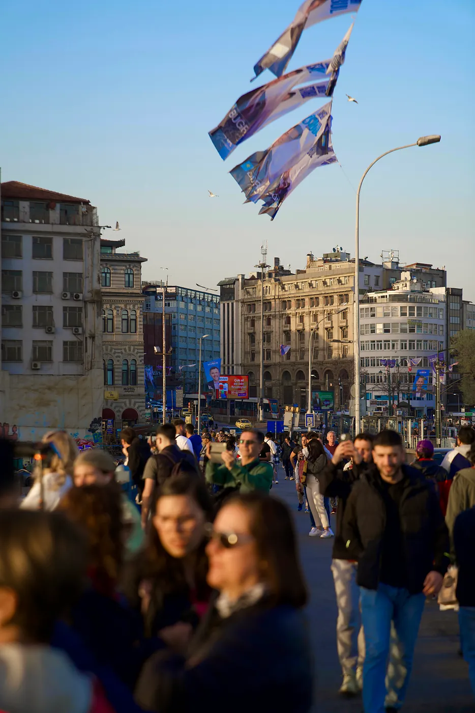 People on the Galata bridge taking photos of the sunset.