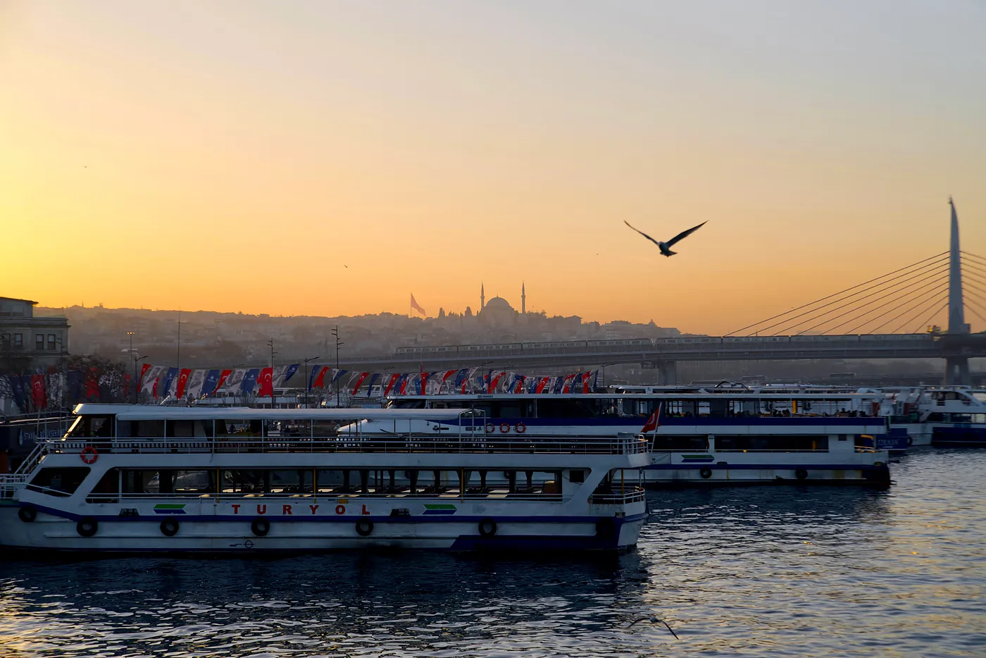 Ferry boats in front of the Haliç metro bridge and a distant Fatih mosque.