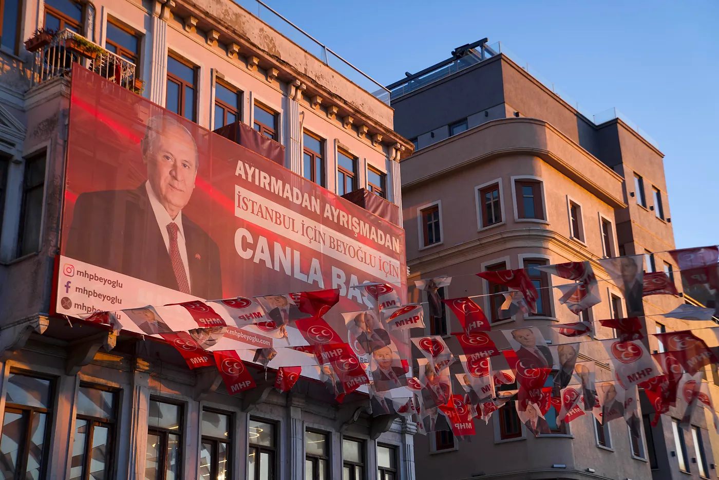 An election billboard accompanied by patriotic flags.