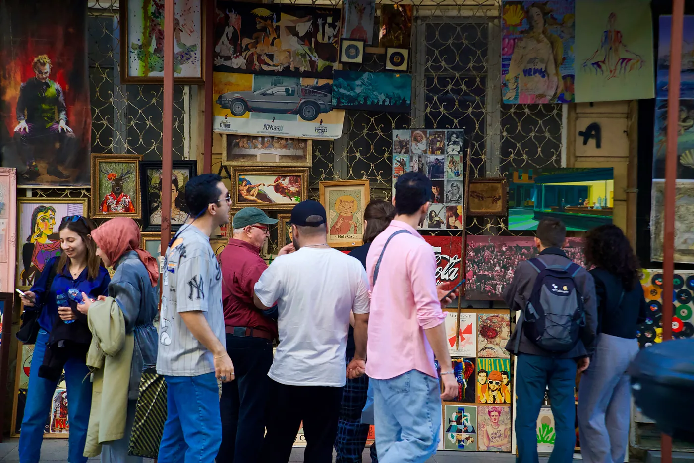Turks and tourists inspecting a wall lined with art.