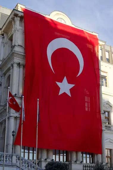 A giant Turkish flag draped down the front of a stone building, Istanbul