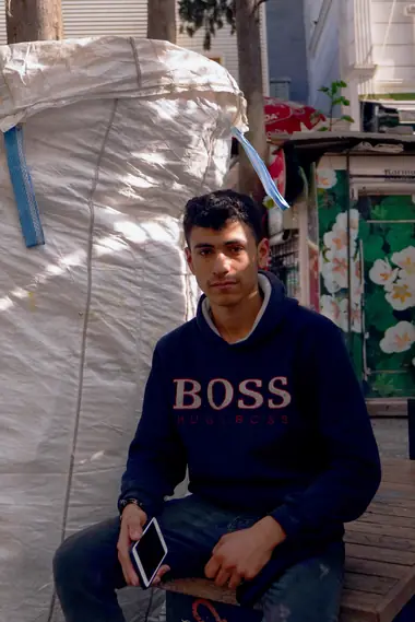 Portrait of a young man in a navy sweatshirt sitting in a doorway, Istanbul